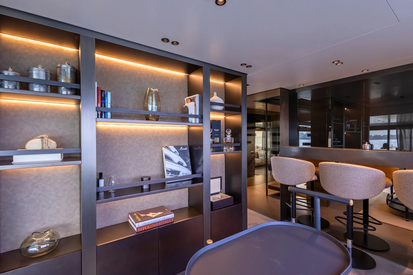 The yacht's lounge area features elegant shelving with ambient lighting and comfortable seating. aboard ILIA Yacht for Sale