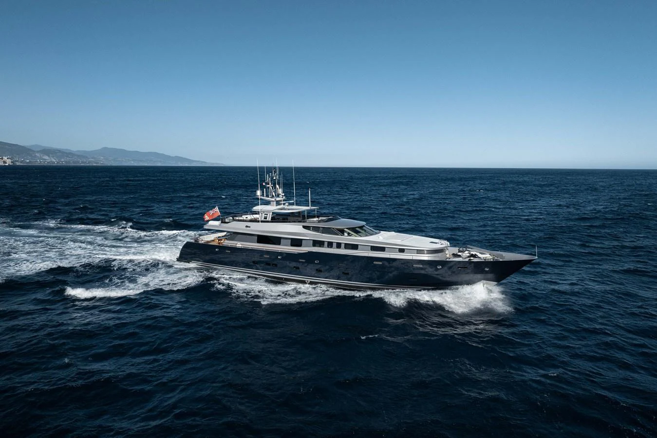 A sleek yacht cruises through the open sea under a clear blue sky. aboard AURA Yacht for Sale