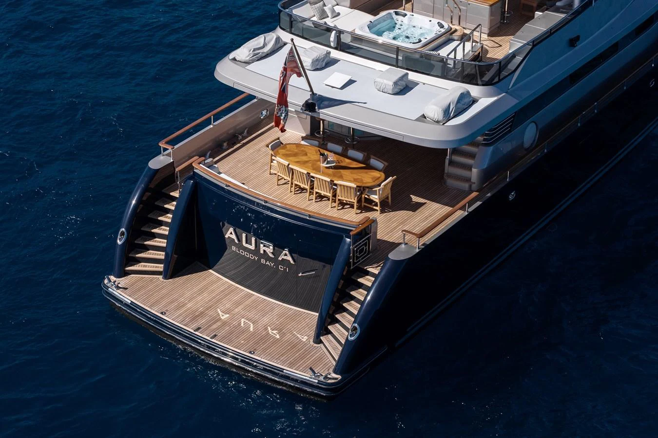 The yacht's aft deck features an elegant dining area and a jacuzzi, perfect for luxurious relaxation at sea. aboard AURA Yacht for Sale