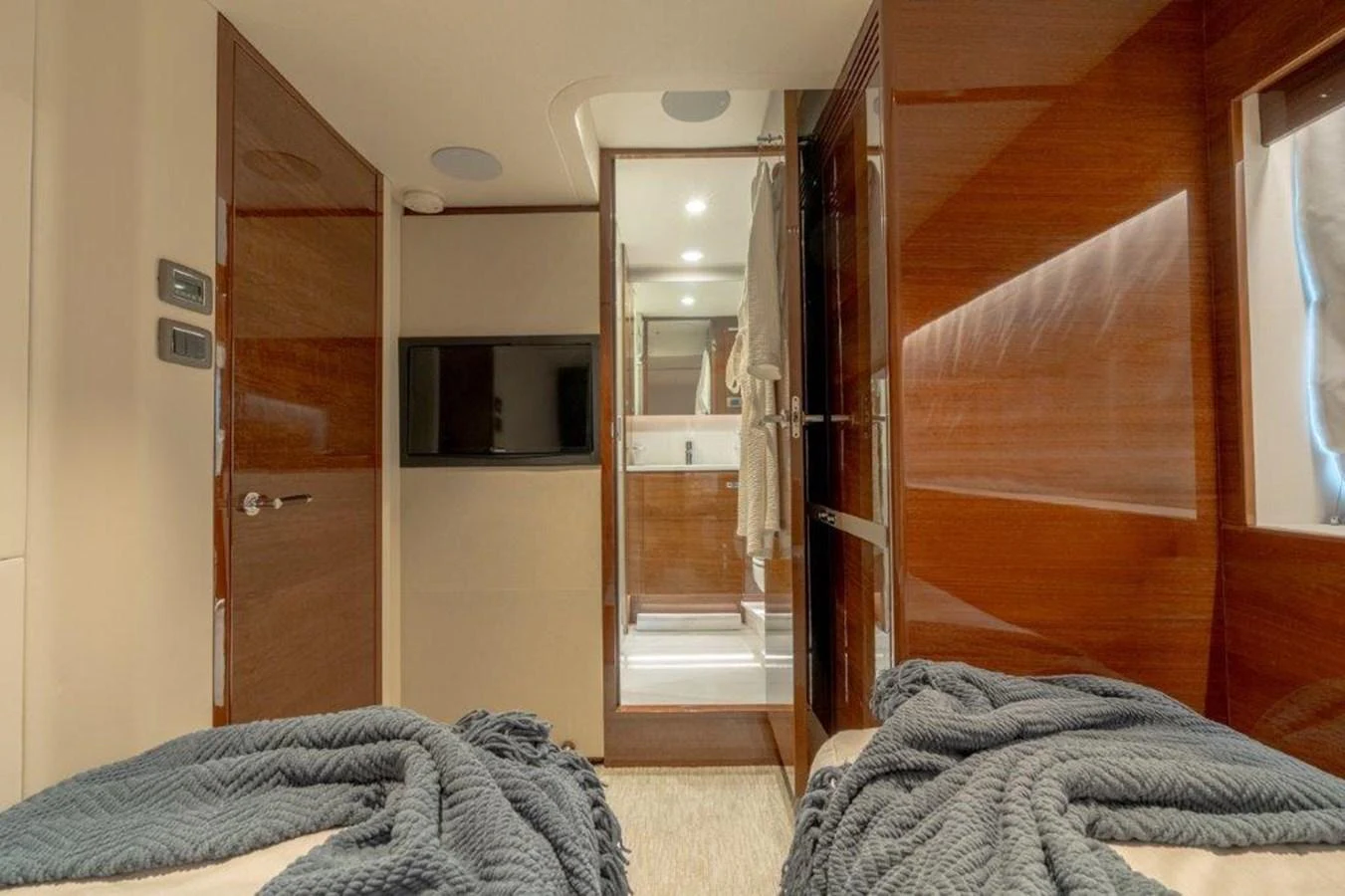The guest cabin features twin beds with cozy blankets and a view into the ensuite bathroom. aboard KAOS Yacht for Sale