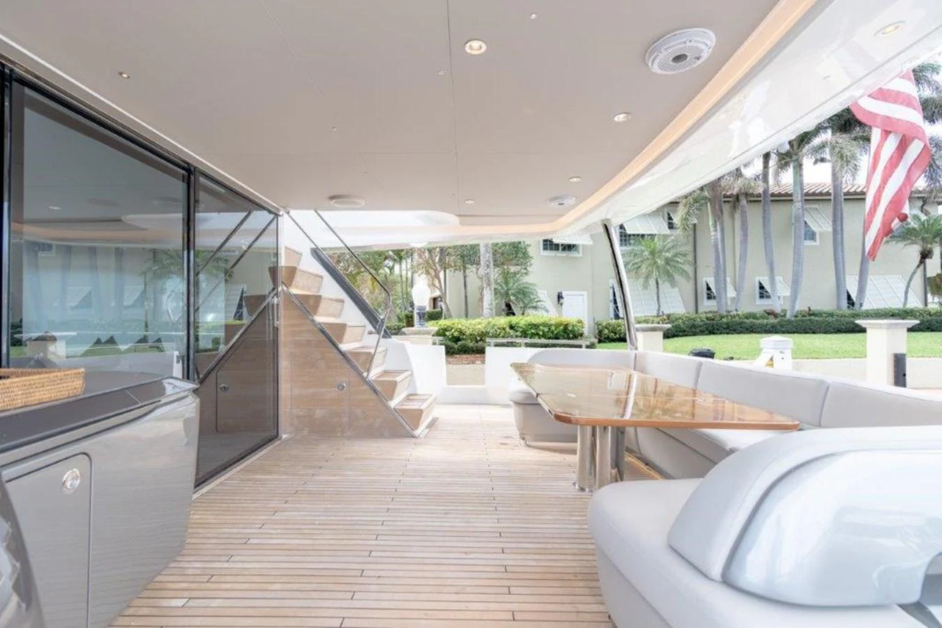 The aft deck features a spacious seating area with a polished wooden table and modern design elements. aboard KAOS Yacht for Sale