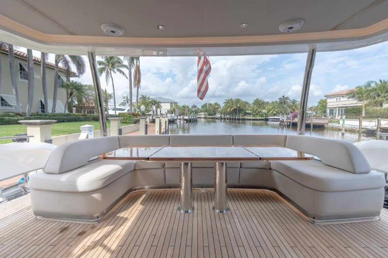 The aft deck features a spacious seating area with a polished wooden table, perfect for enjoying the view of the marina. aboard KAOS Yacht for Sale