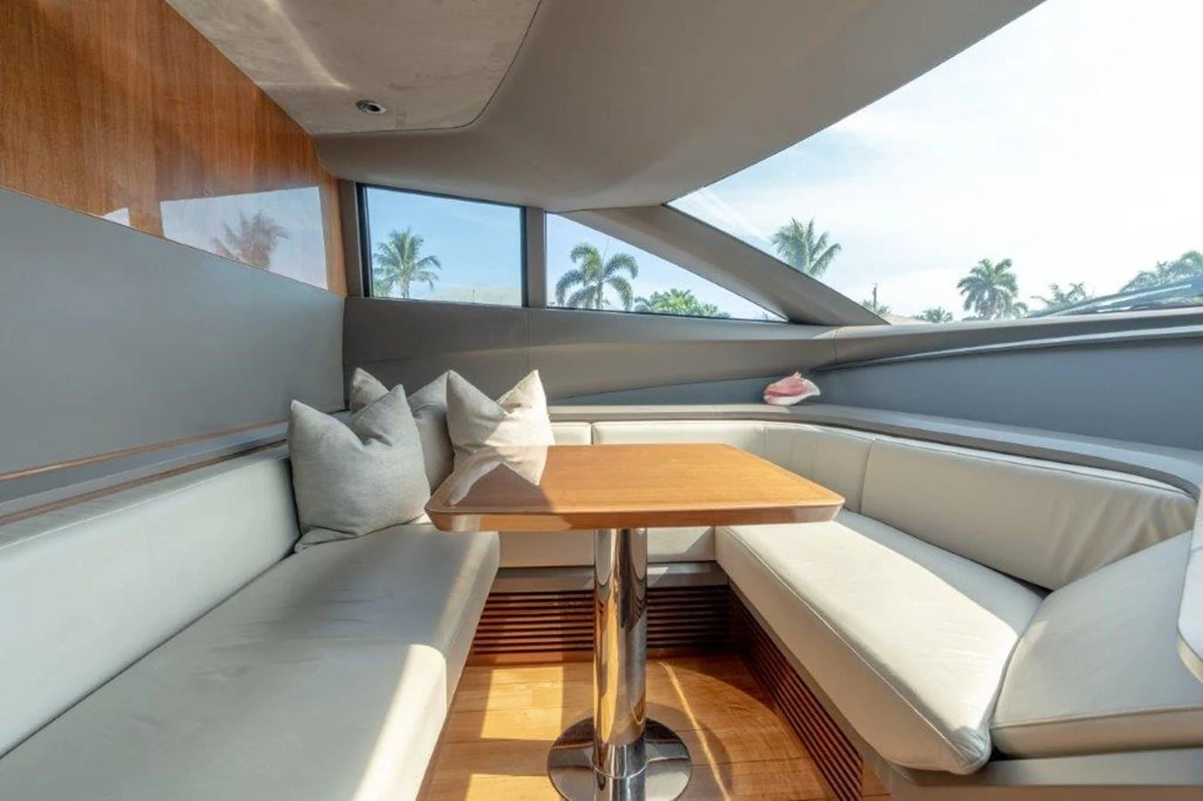 The saloon features a cozy seating area with a wooden table and ample natural light. aboard KAOS Yacht for Sale