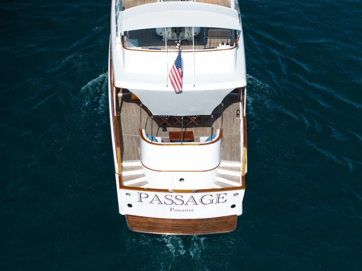 The yacht's aft deck features a spacious area with elegant wood finishes and an American flag. aboard PASSAGE Yacht for Sale