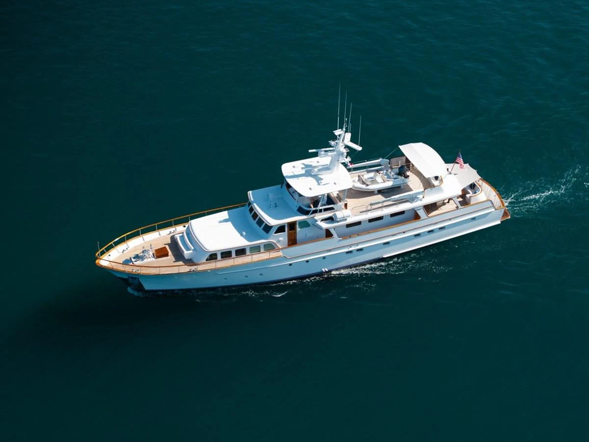 A pristine white yacht cruises smoothly on clear blue waters, showcasing its elegant design and spacious decks. aboard PASSAGE Yacht for Sale