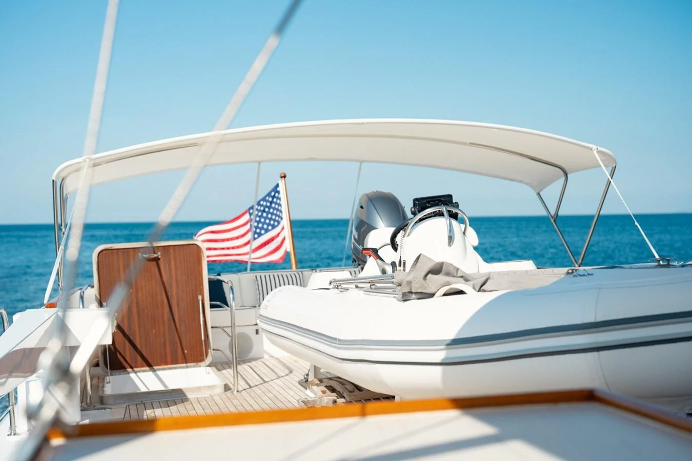 The aft deck features a tender and a shaded seating area, perfect for relaxation. aboard PASSAGE Yacht for Sale