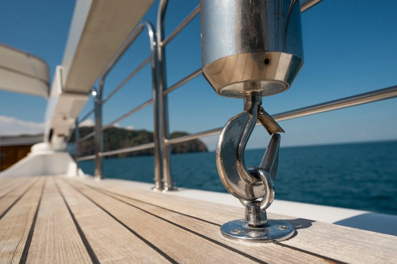 A close-up of a polished metal hook on the yacht's deck with a scenic ocean backdrop. aboard PASSAGE Yacht for Sale