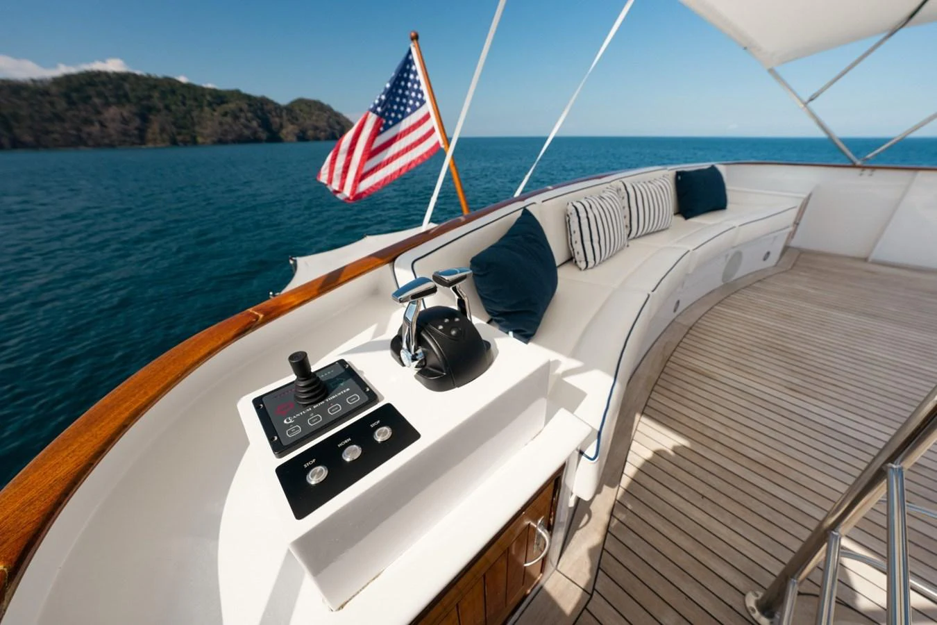 The aft deck features a comfortable seating area with an American flag waving in the background. aboard PASSAGE Yacht for Sale
