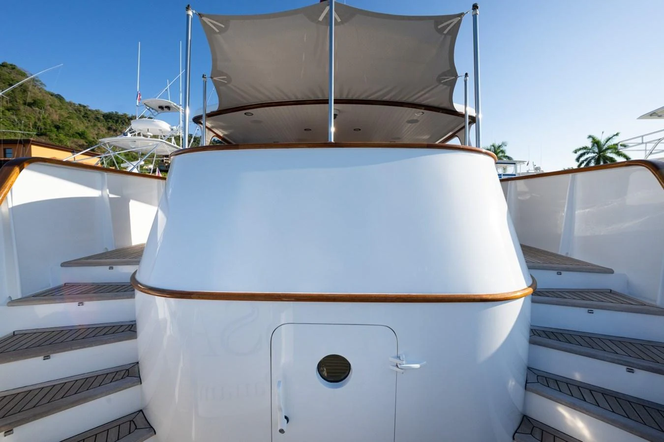 The yacht's exterior features a sleek, curved design with a clean white finish and wooden accents. aboard PASSAGE Yacht for Sale