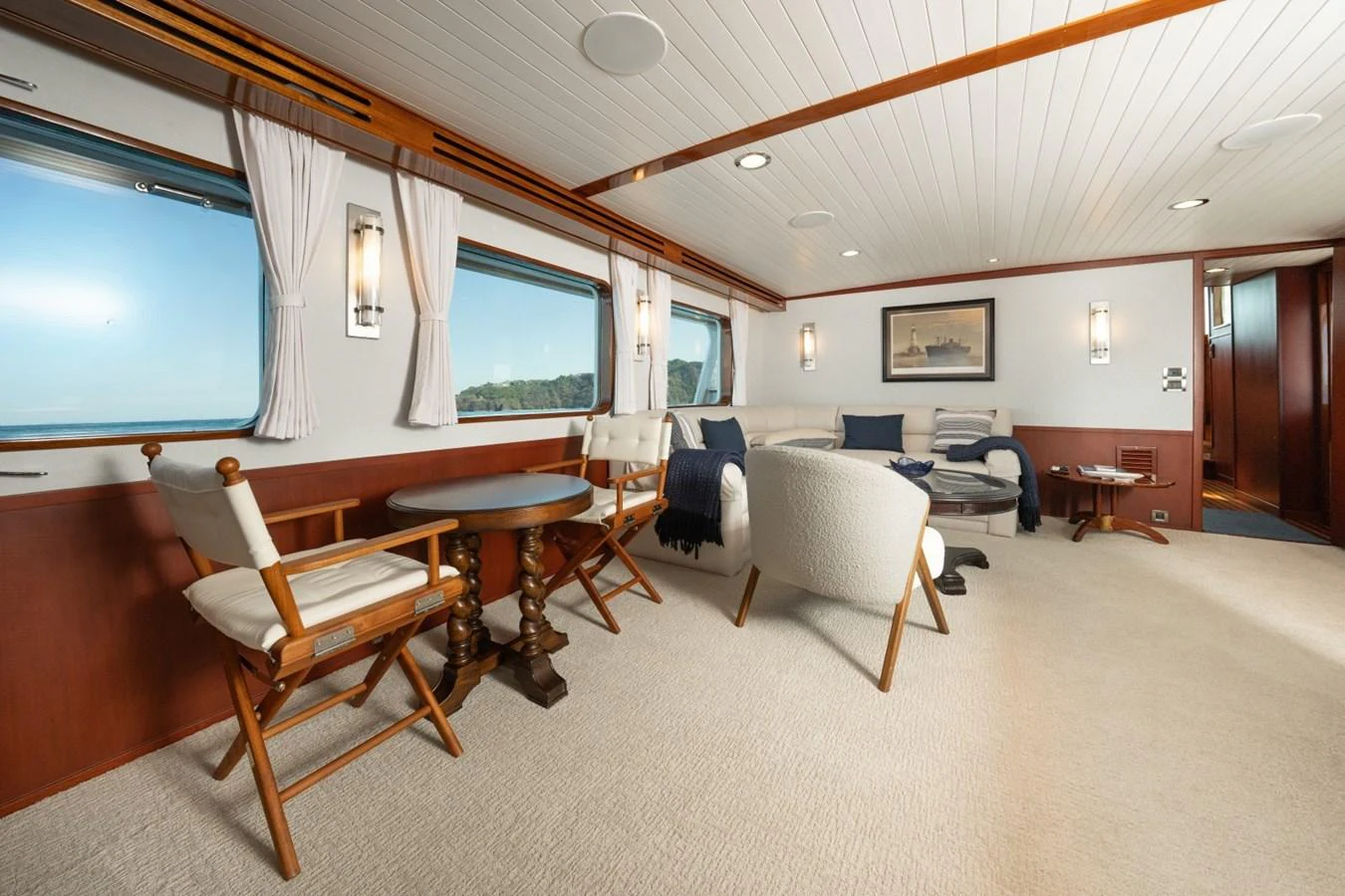 The yacht's interior features a spacious and elegantly furnished lounge area with large windows offering scenic views. aboard PASSAGE Yacht for Sale
