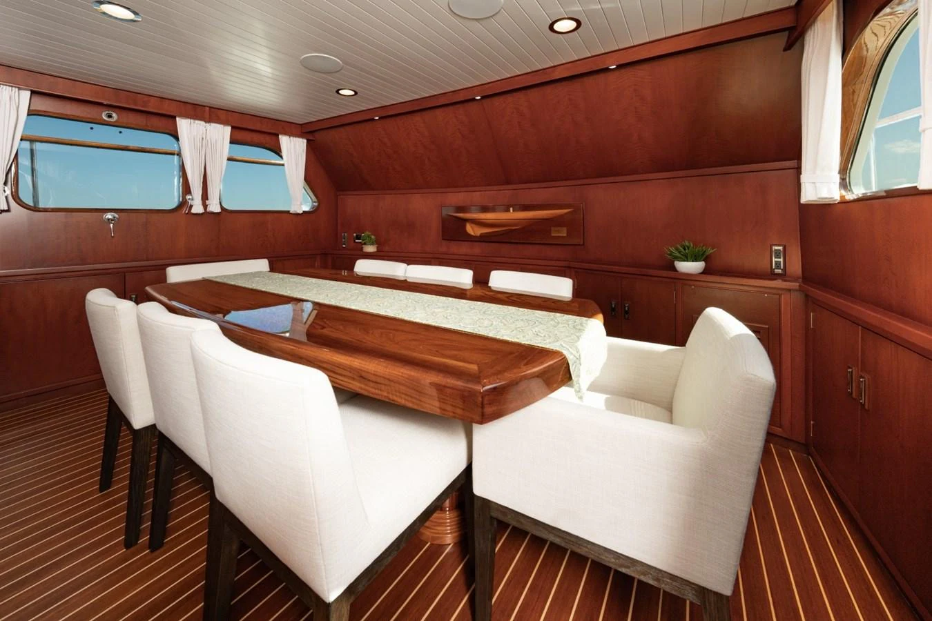 The yacht's dining area features a polished wooden table surrounded by plush white chairs, creating an inviting space for meals. aboard PASSAGE Yacht for Sale
