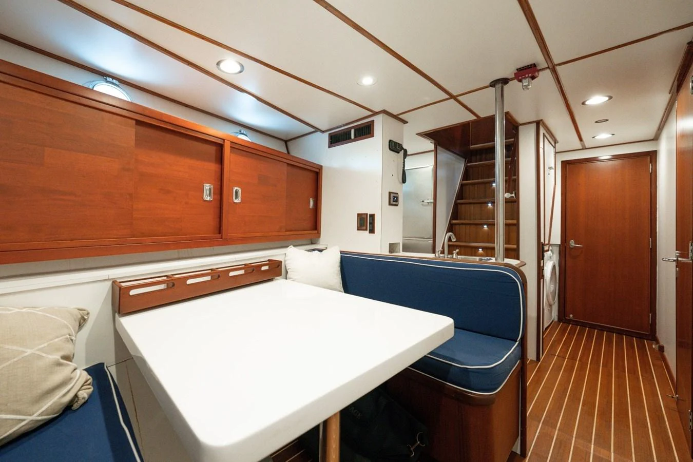 The yacht's dining area features a cozy seating arrangement with a wooden finish and modern lighting. aboard PASSAGE Yacht for Sale
