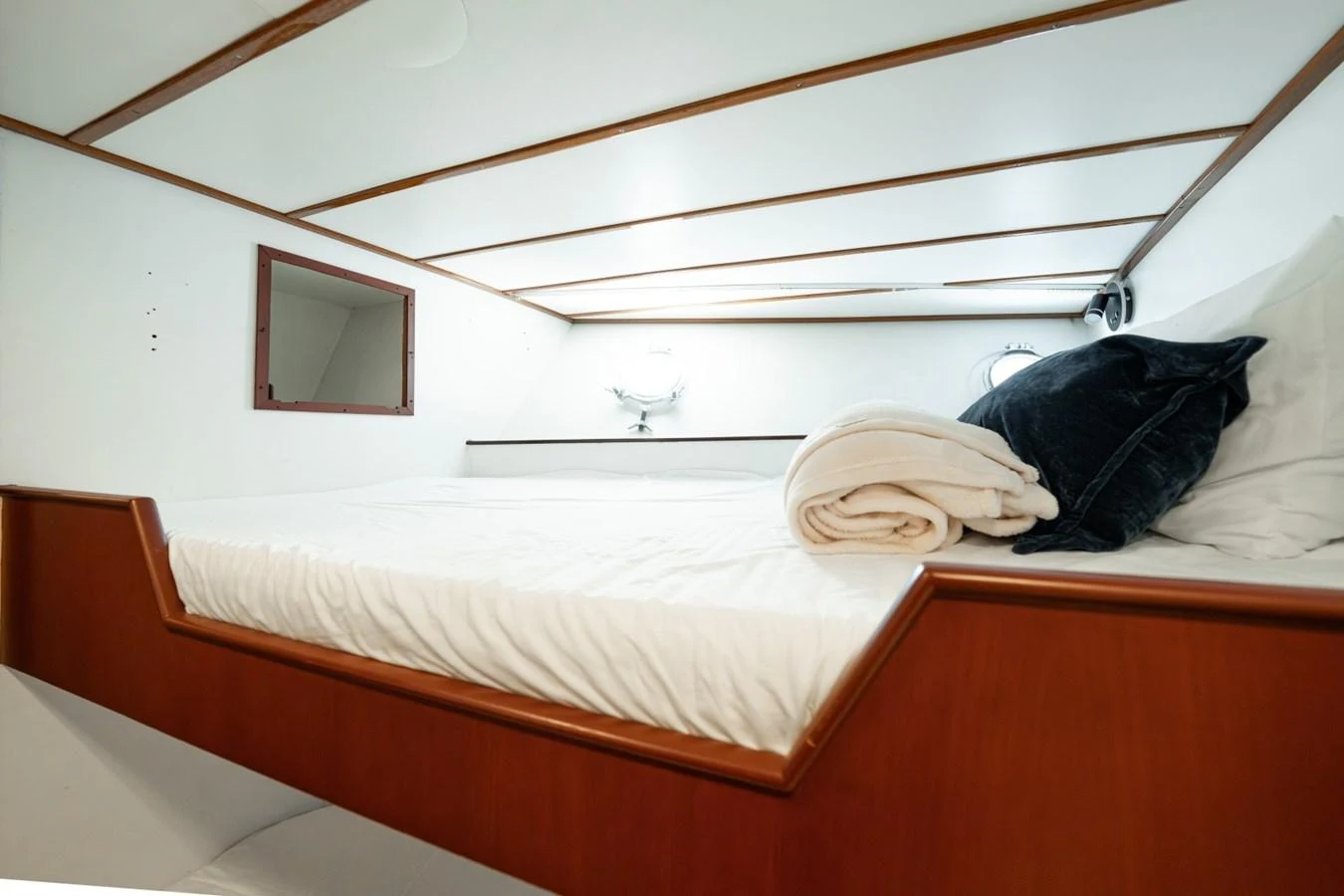 The cozy cabin features a comfortable bed with plush pillows and a neatly folded towel. aboard PASSAGE Yacht for Sale