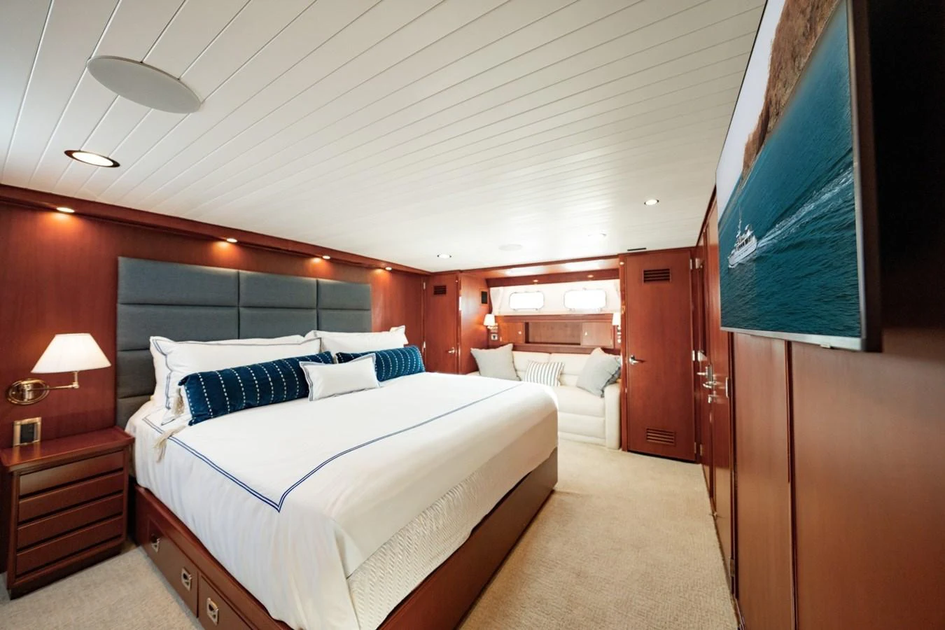 The master stateroom features a spacious bed, elegant wood paneling, and a cozy seating area. aboard PASSAGE Yacht for Sale