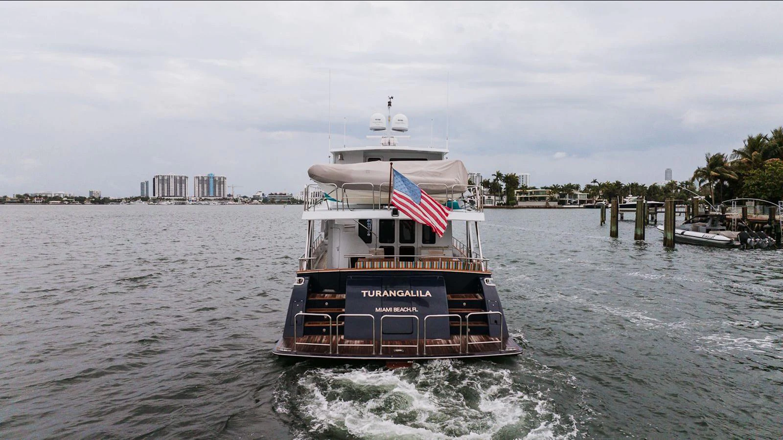 The yacht is cruising away from the camera, showcasing its elegant stern and flag. aboard TURANGALILA Yacht for Sale