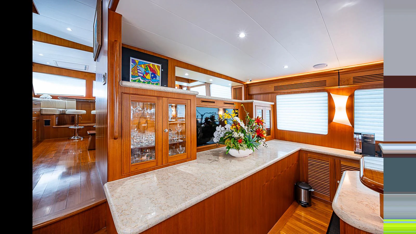 The yacht's galley features elegant wood cabinetry, a marble countertop, and a floral centerpiece, creating a warm and inviting atmosphere. aboard TURANGALILA Yacht for Sale