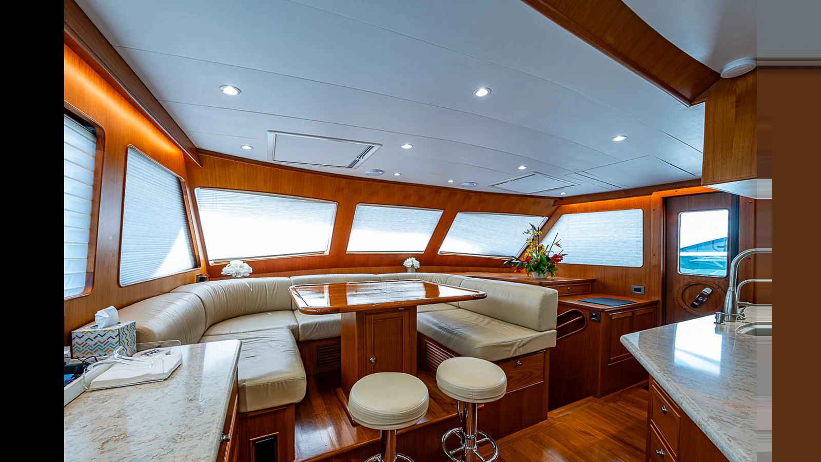 The salon features a cozy seating area with a dining table and bar stools, surrounded by large windows for ample natural light. aboard TURANGALILA Yacht for Sale