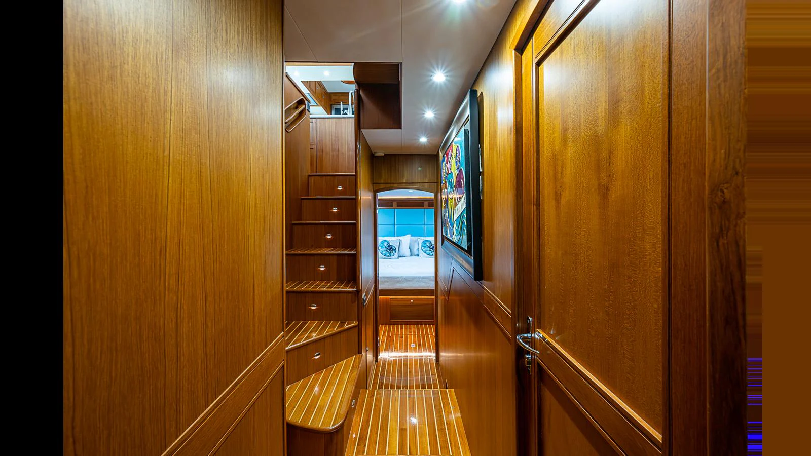 A warm, wood-paneled hallway leads to a cozy stateroom with ambient lighting. aboard TURANGALILA Yacht for Sale