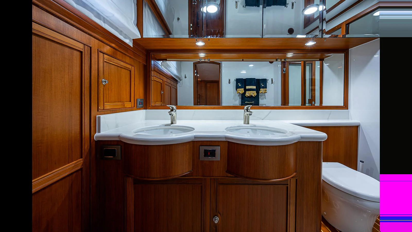 A luxurious yacht bathroom featuring dual sinks and elegant wooden cabinetry. aboard TURANGALILA Yacht for Sale