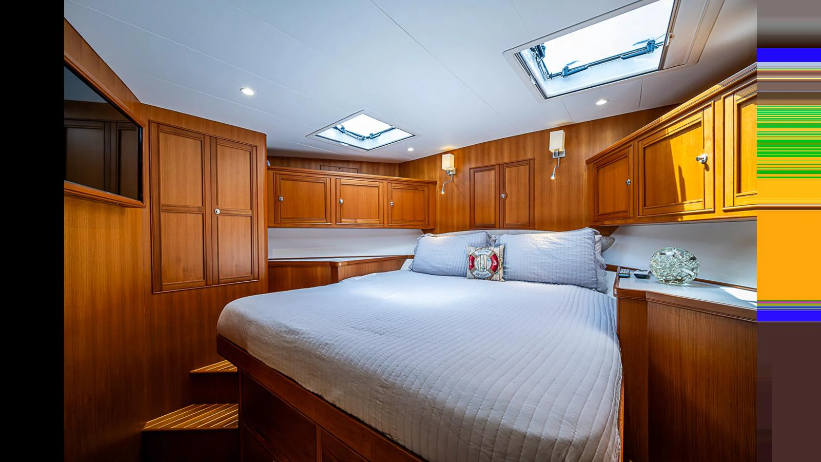 The stateroom features a spacious bed with elegant wooden cabinetry and ample natural light from overhead hatches. aboard TURANGALILA Yacht for Sale