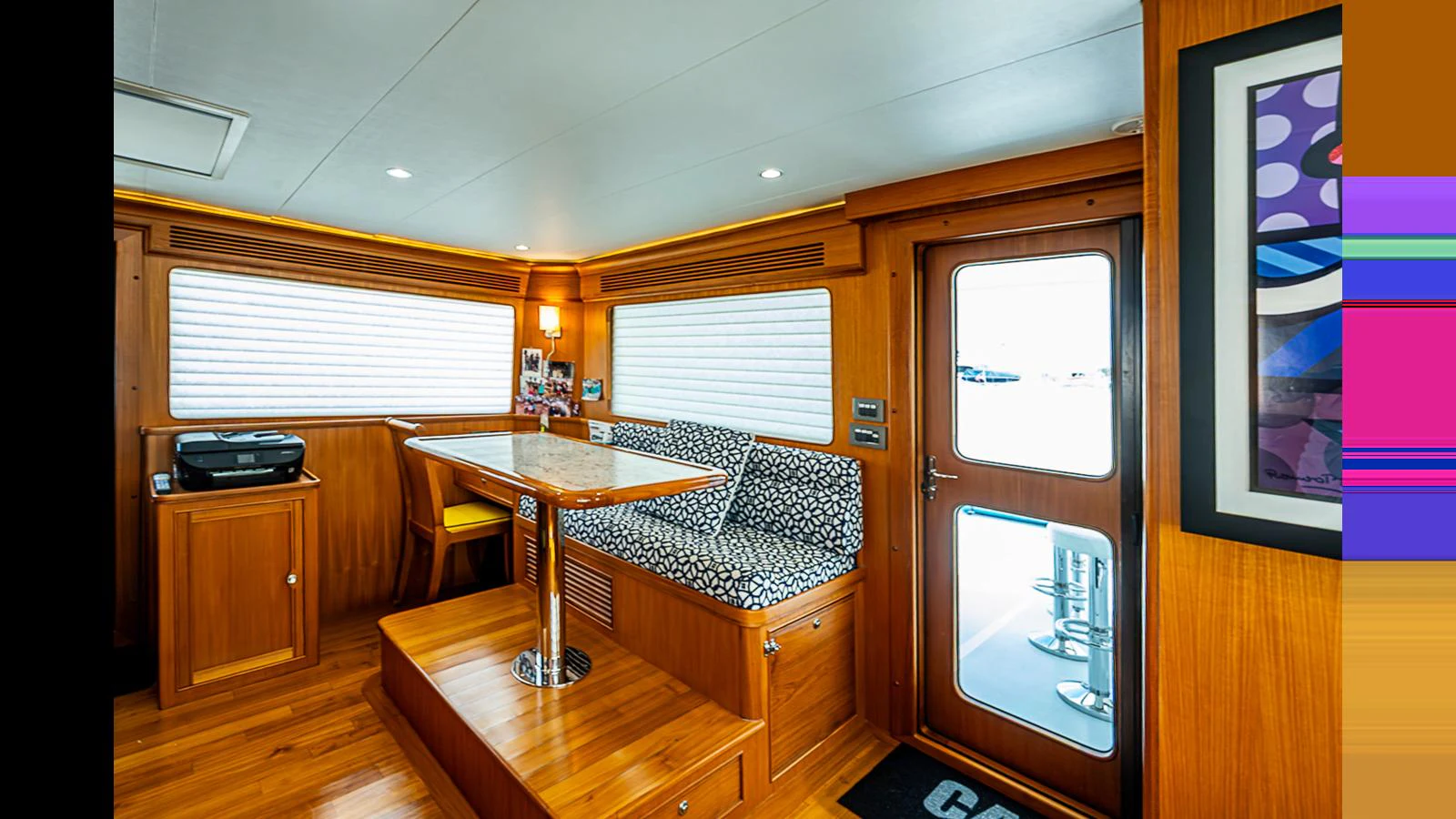 A cozy dining area with a wooden table and cushioned seating, complemented by natural light through the windows. aboard TURANGALILA Yacht for Sale