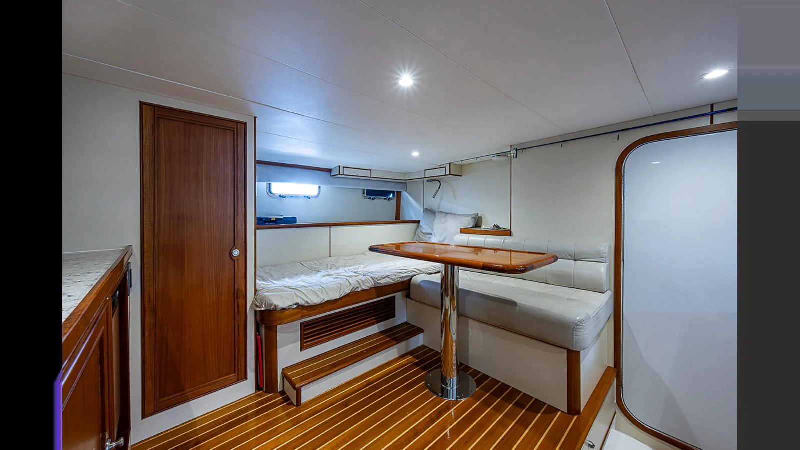 The cabin features a cozy seating area with a wooden table and a comfortable bed, all set in a warm, inviting ambiance. aboard TURANGALILA Yacht for Sale