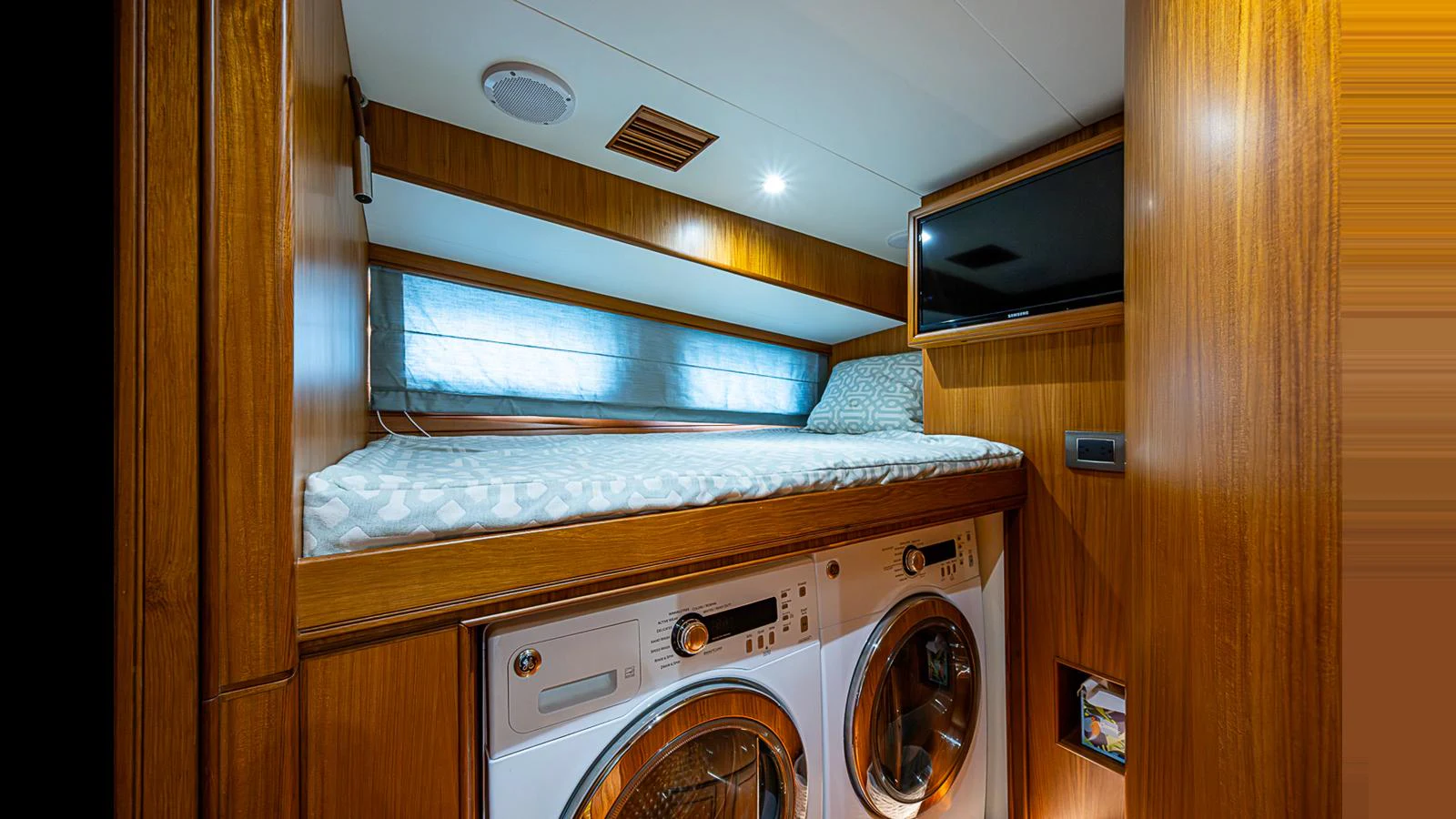 The yacht's laundry room features a cozy bunk bed above modern washer and dryer units. aboard TURANGALILA Yacht for Sale