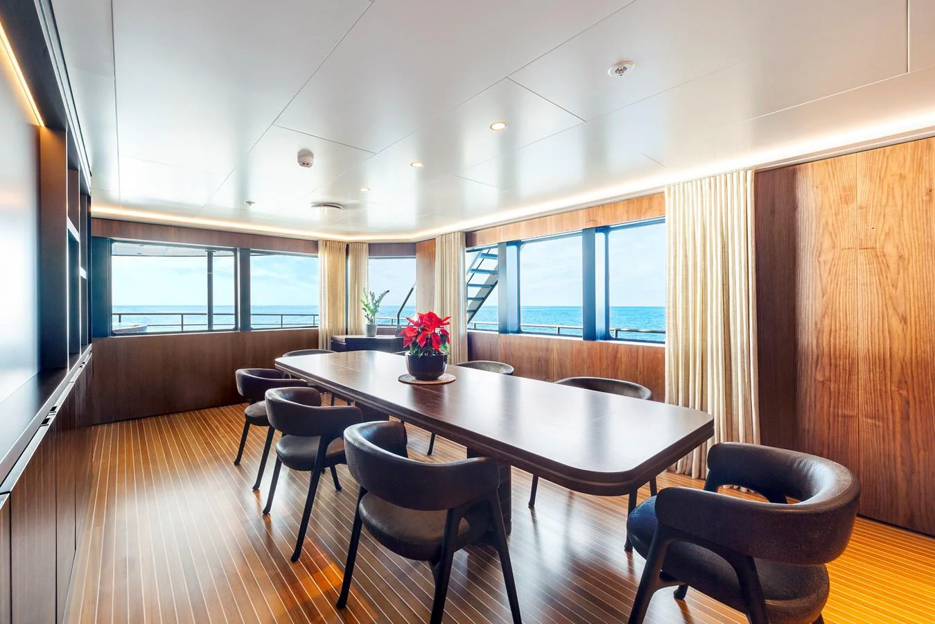 The yacht's dining area features a sleek table with comfortable seating and panoramic ocean views. aboard NURJA Yacht for Sale
