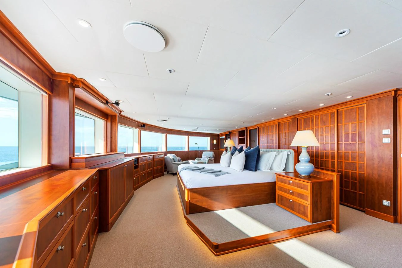 The master stateroom features expansive windows, luxurious wood finishes, and a spacious bed for ultimate comfort. aboard NURJA Yacht for Sale