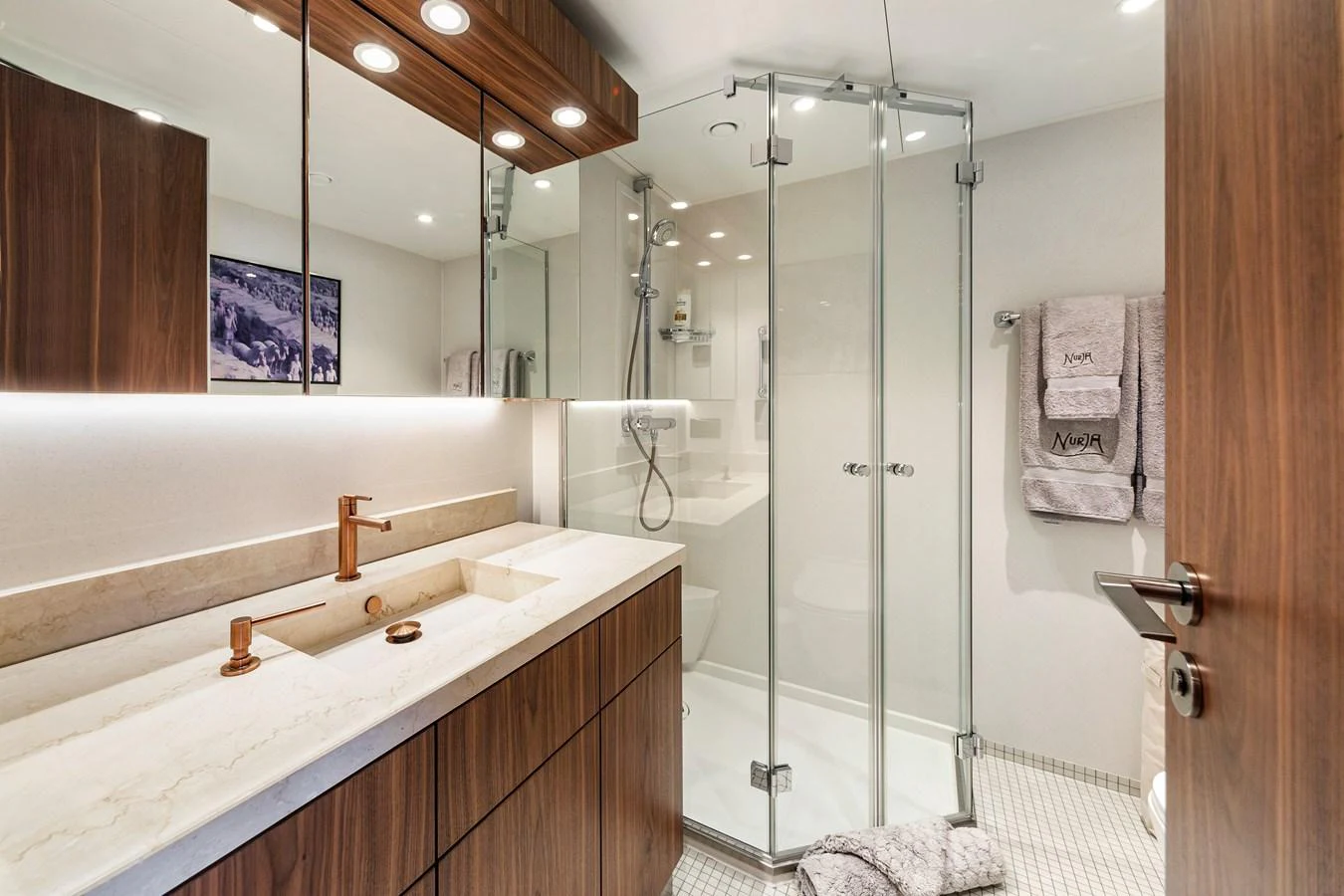 The yacht's bathroom features a modern design with a glass-enclosed shower and elegant wooden cabinetry. aboard NURJA Yacht for Sale