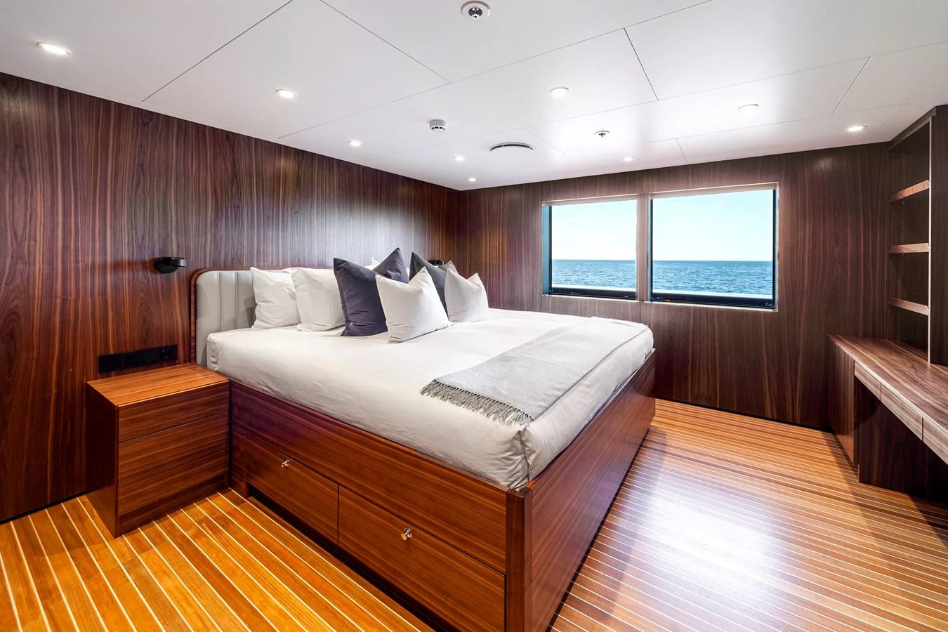 The master stateroom features a luxurious bed with a stunning ocean view through large windows. aboard NURJA Yacht for Sale