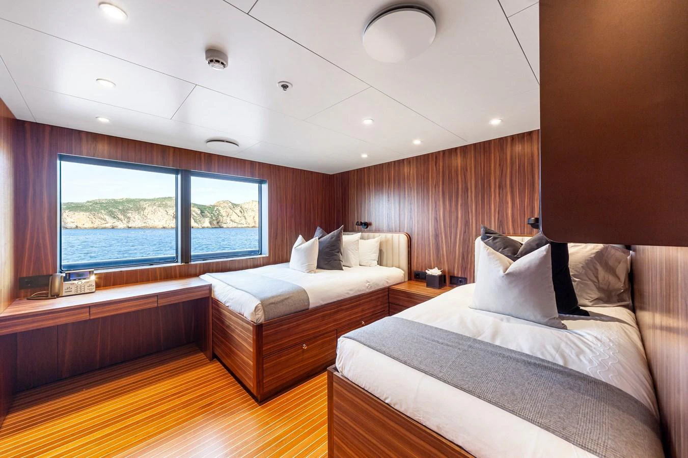 The guest stateroom features two twin beds with a stunning view of the sea through large windows. aboard NURJA Yacht for Sale