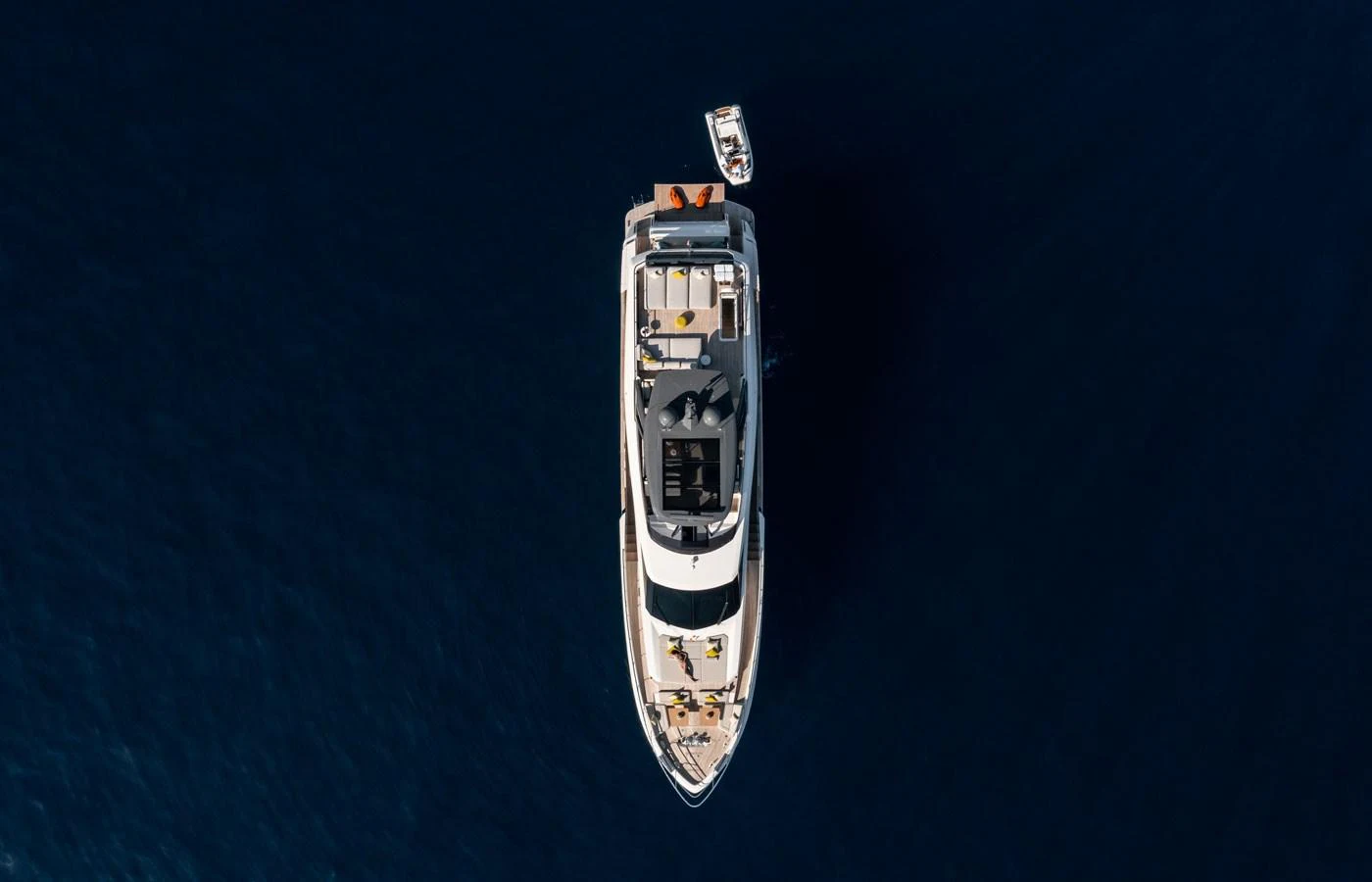 Aerial view of a luxurious yacht cruising on deep blue waters with a tender boat trailing behind. aboard ALEGRIA II Yacht for Sale