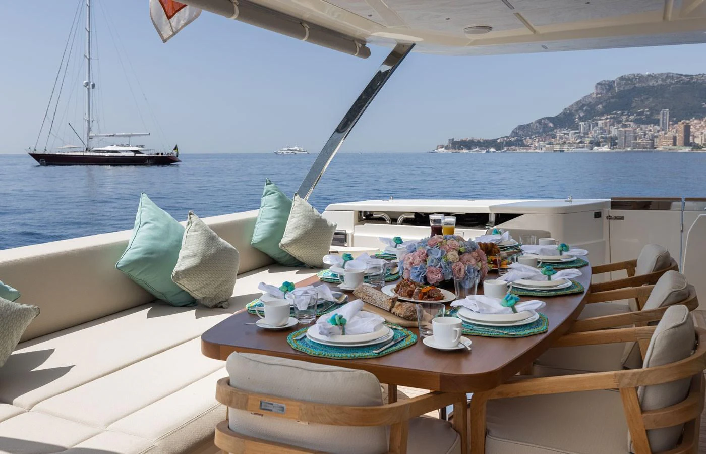 The aft deck features a beautifully set dining table with a stunning view of the sea and coastline. aboard ALEGRIA II Yacht for Sale