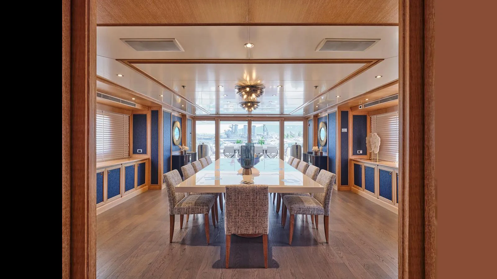 The yacht's dining area features a long table with elegant seating and large windows offering a scenic view. aboard THEOLINA Yacht for Sale