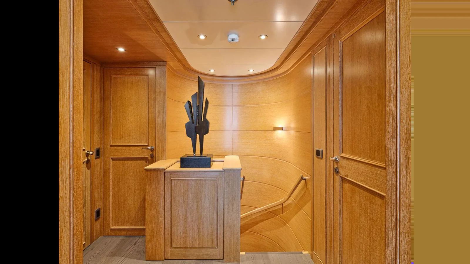 The yacht's interior features elegant wood paneling and a modern sculpture, creating a sophisticated ambiance. aboard THEOLINA Yacht for Sale