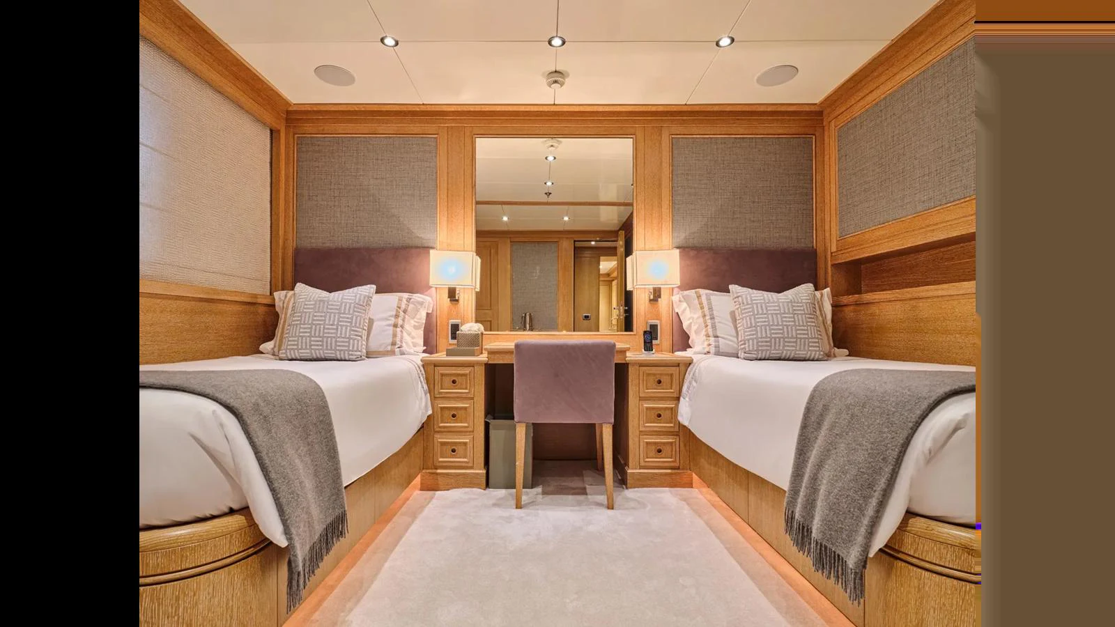 The guest stateroom features twin beds, a central vanity, and warm wood accents. aboard THEOLINA Yacht for Sale