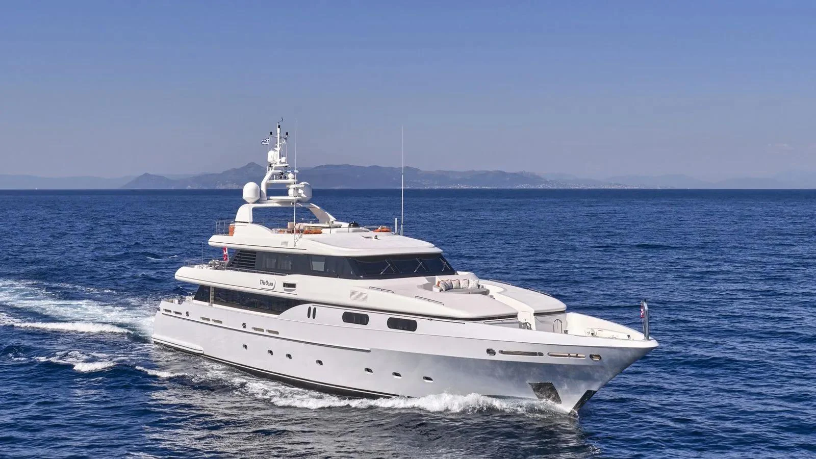 A sleek and elegant yacht cruising on the open sea under a clear blue sky. aboard THEOLINA Yacht for Sale