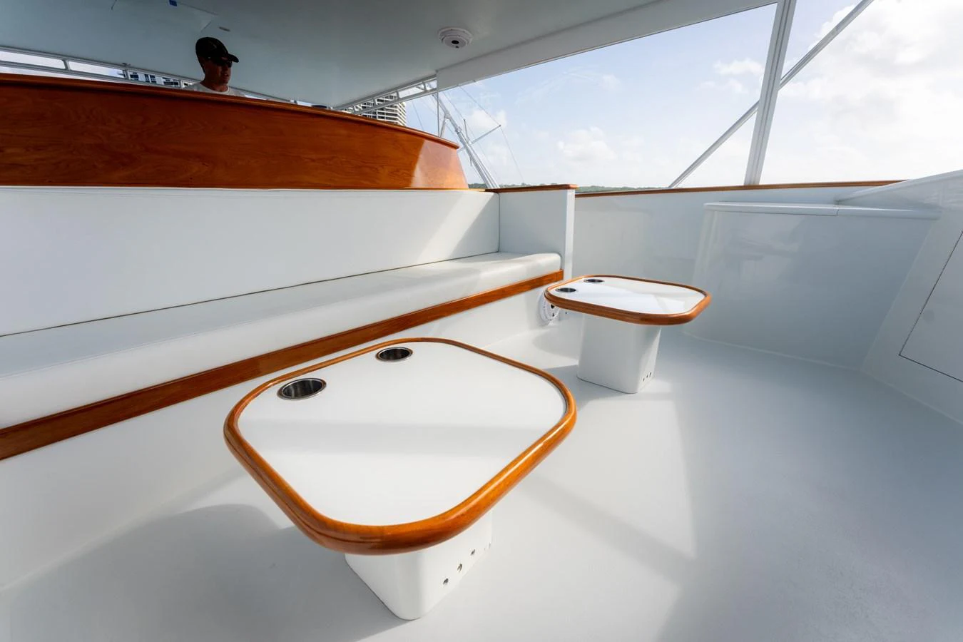 The flybridge features sleek white seating with polished wooden accents and modern tables. aboard WISH YOU WERE HERE Yacht for Sale