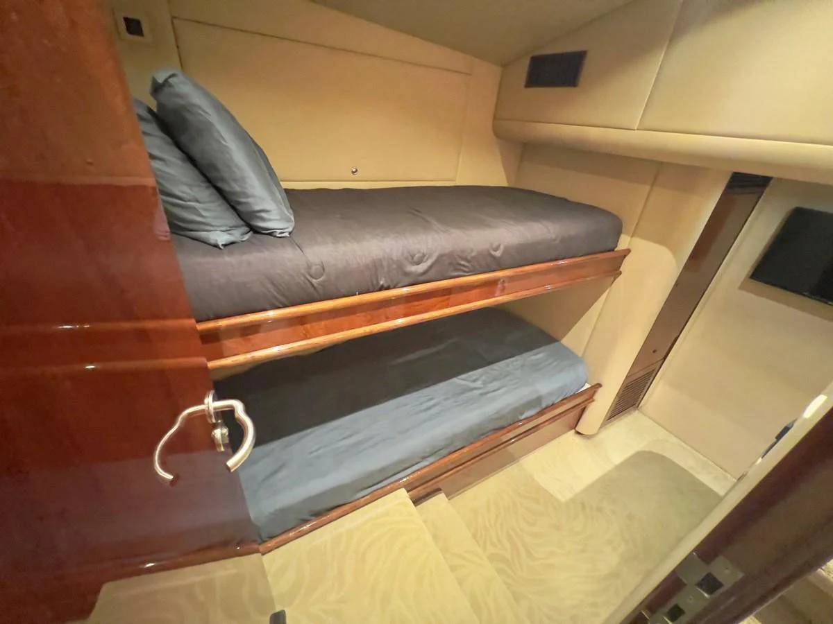The cozy bunk cabin features two neatly made beds with dark bedding and a polished wooden finish. aboard WISH YOU WERE HERE Yacht for Sale