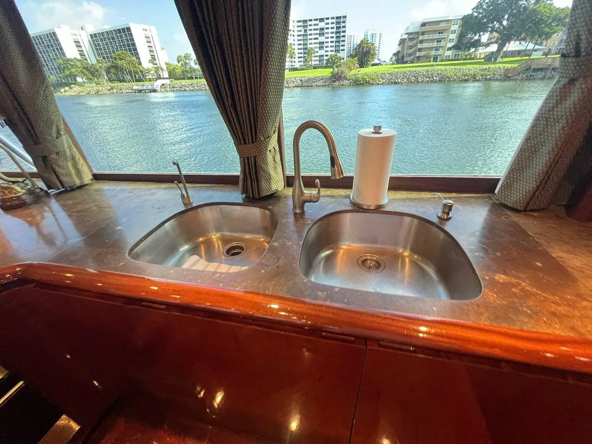 The galley features a double sink with a view of the water through large windows. aboard WISH YOU WERE HERE Yacht for Sale