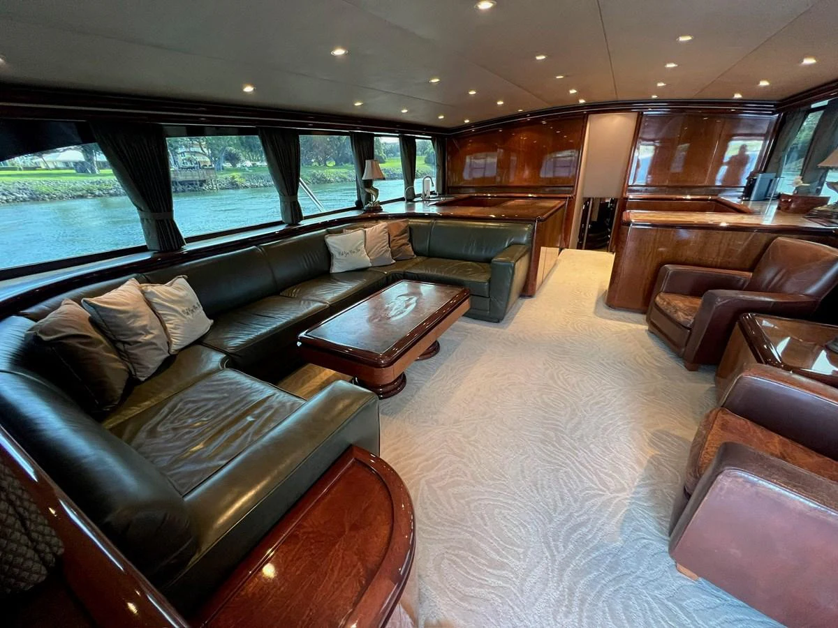 The yacht's salon features plush seating, elegant wooden finishes, and large windows offering scenic views. aboard WISH YOU WERE HERE Yacht for Sale