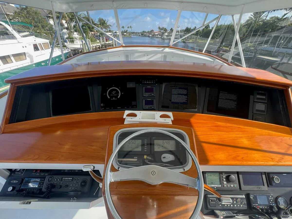 The helm station features a polished wooden dashboard with advanced navigation instruments and a sleek steering wheel. aboard WISH YOU WERE HERE Yacht for Sale