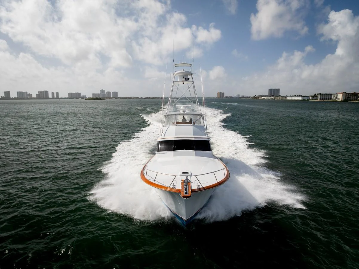 A sleek yacht cuts through the water with a powerful presence under a partly cloudy sky. aboard WISH YOU WERE HERE Yacht for Sale