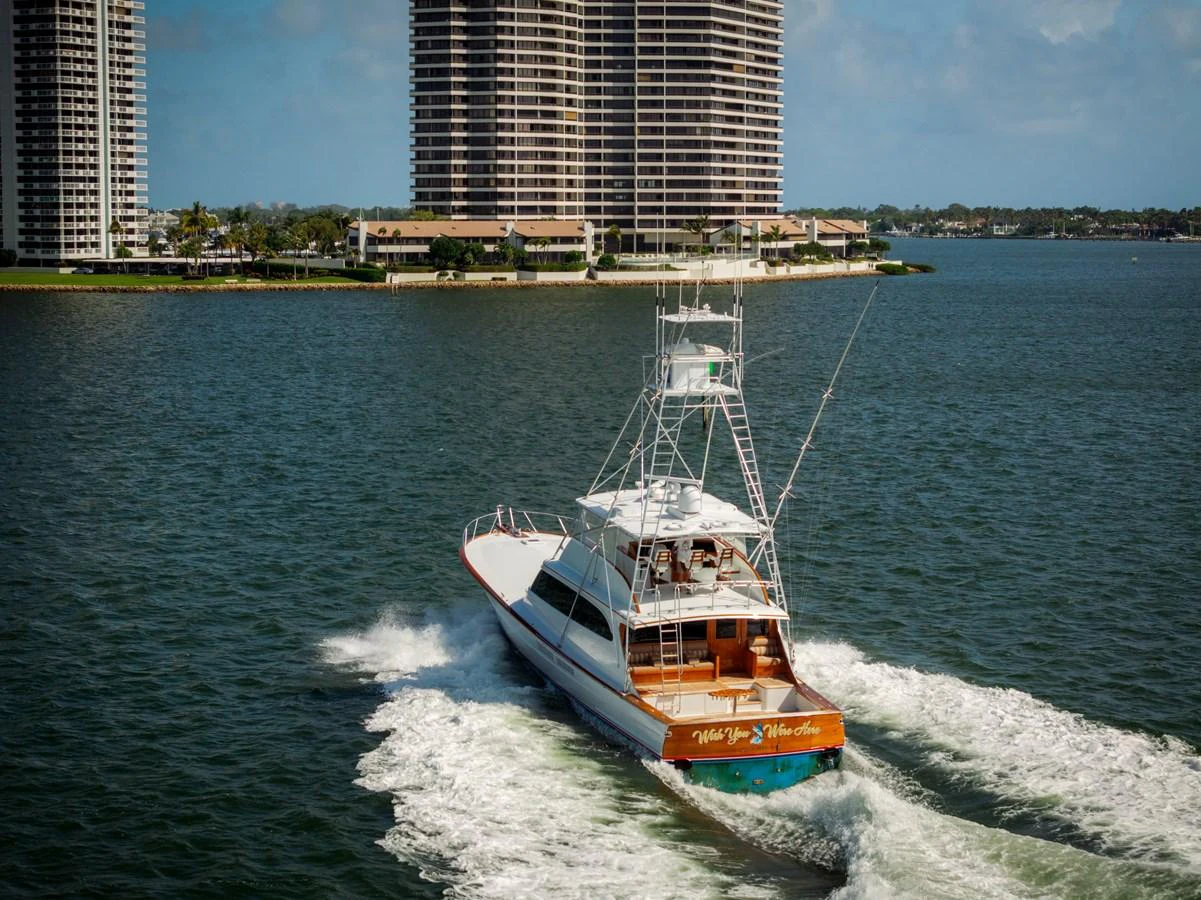 A sleek yacht cruises through the water with a cityscape in the background. aboard WISH YOU WERE HERE Yacht for Sale