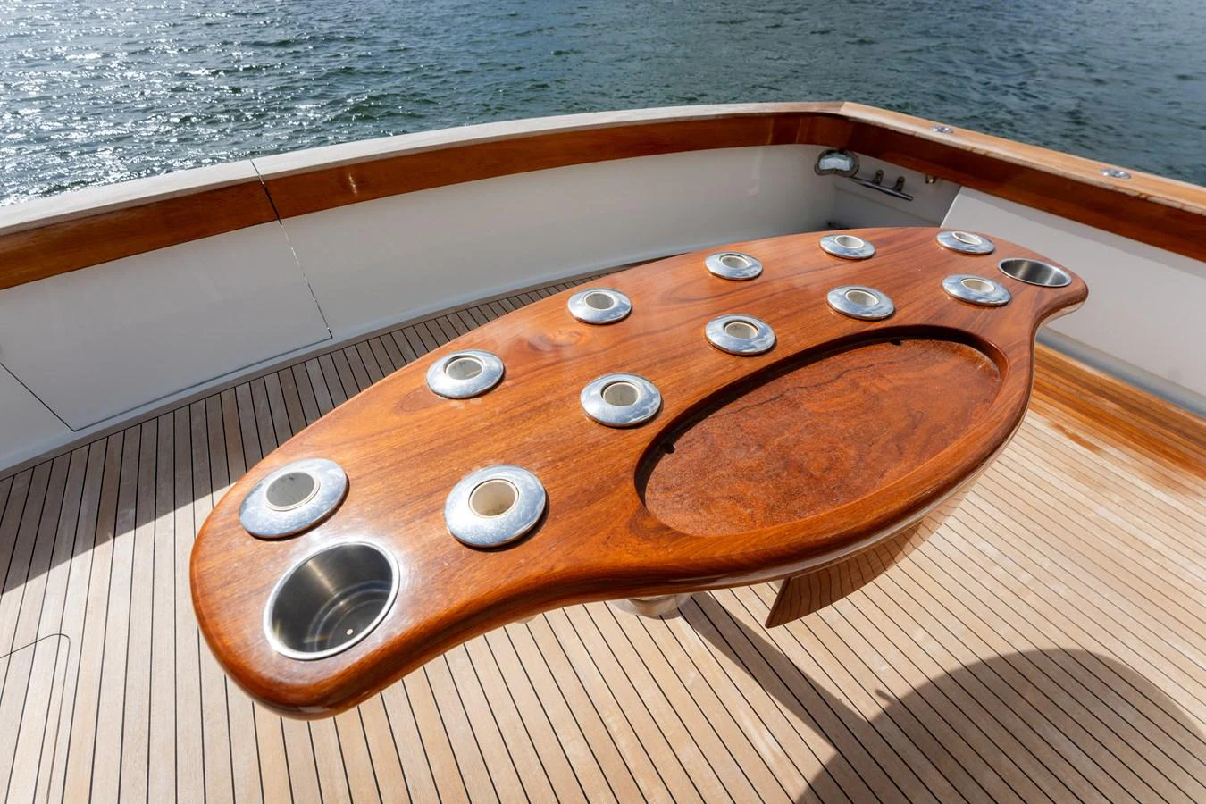 The aft deck features a beautifully crafted wooden table with multiple cup holders, perfect for outdoor gatherings. aboard WISH YOU WERE HERE Yacht for Sale