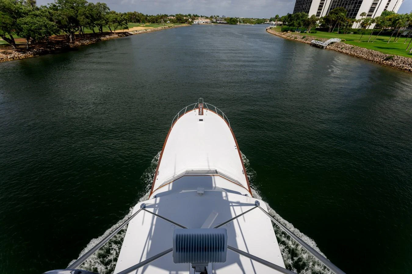 The yacht cruises through a serene waterway, offering a view from the bow. aboard WISH YOU WERE HERE Yacht for Sale