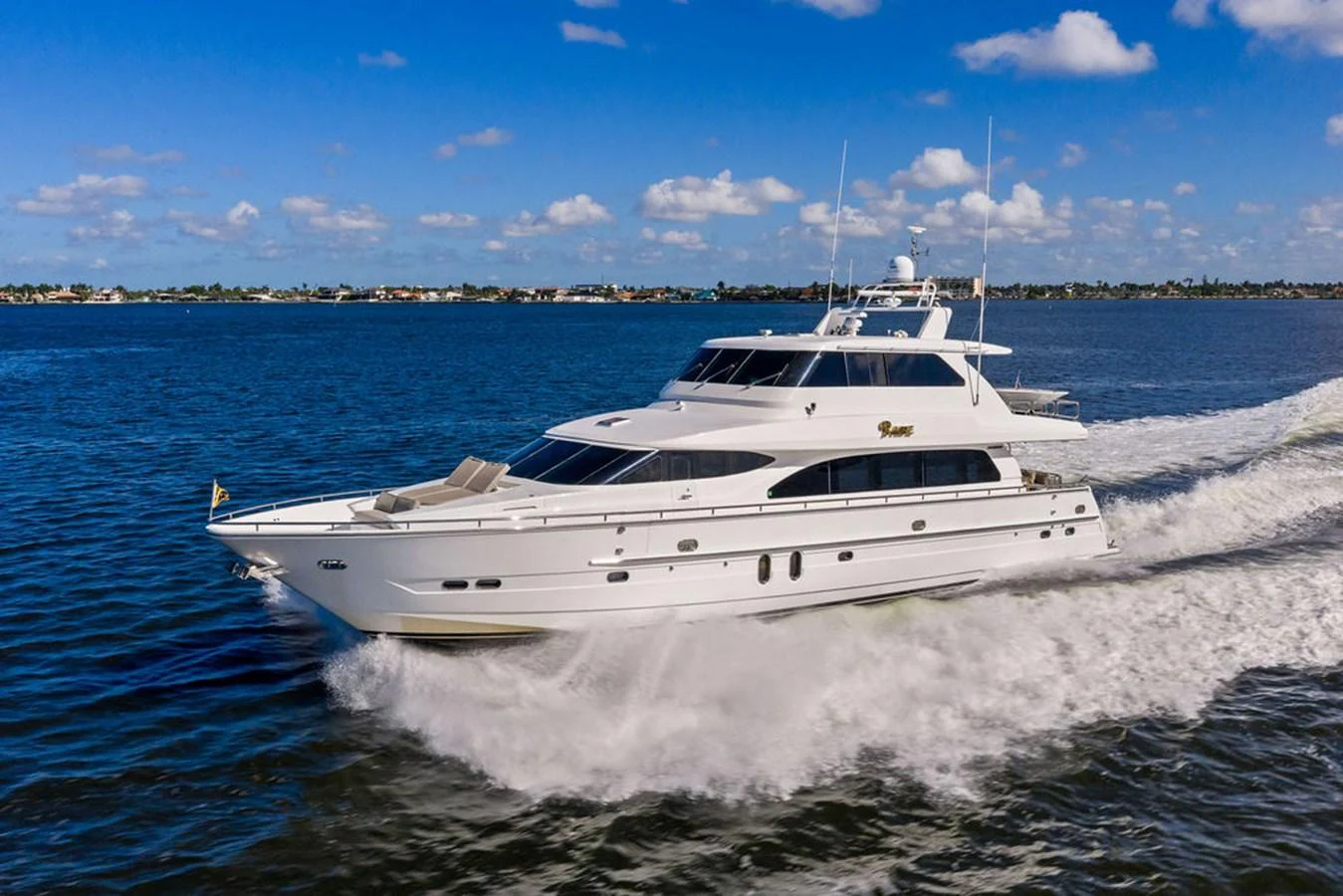 A sleek white yacht cruises swiftly through calm blue waters under a bright sky. aboard BABE Yacht for Sale