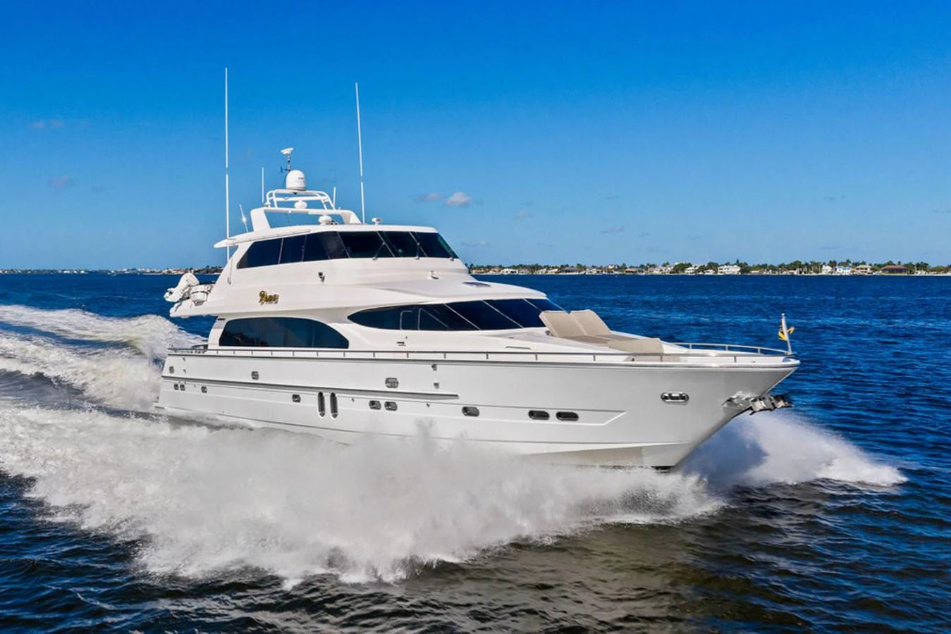 A sleek white yacht cruises swiftly on open water under a clear blue sky. aboard BABE Yacht for Sale