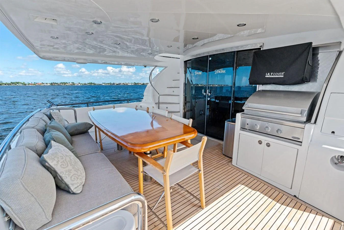The aft deck features a comfortable dining area with a large table and built-in seating, perfect for alfresco meals with a view. aboard BABE Yacht for Sale